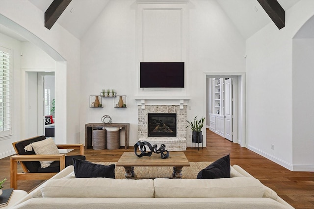 living room with hardwood / wood-style flooring, a brick fireplace, a wealth of natural light, and beam ceiling