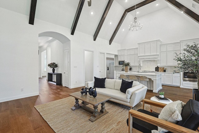 living room featuring an inviting chandelier, dark hardwood / wood-style floors, beam ceiling, and high vaulted ceiling