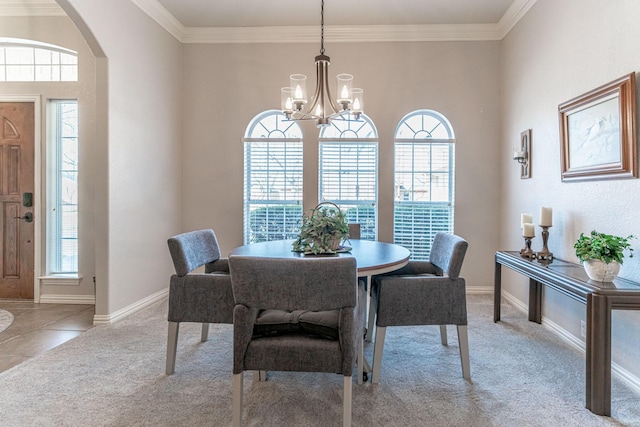 carpeted dining space with arched walkways, crown molding, baseboards, and an inviting chandelier