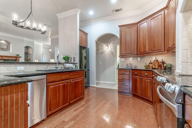 kitchen with arched walkways, stainless steel appliances, a sink, and visible vents