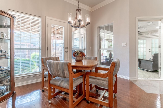 dining space featuring a chandelier, wood finished floors, baseboards, ornamental molding, and french doors