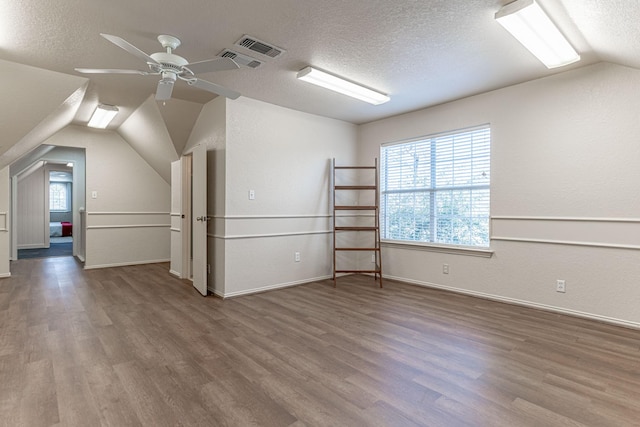 bonus room featuring wood finished floors, lofted ceiling, ceiling fan, and a textured ceiling