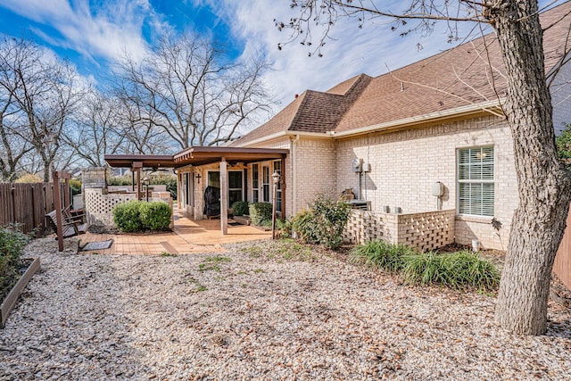 rear view of house featuring ceiling fan, brick siding, a shingled roof, fence, and a patio area