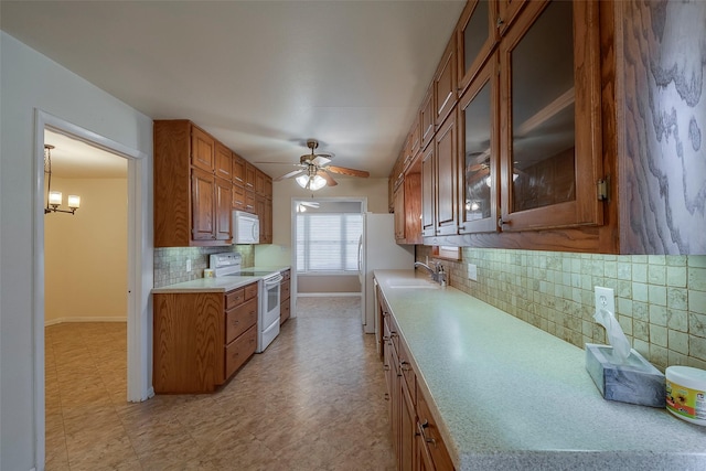 kitchen with sink, ceiling fan with notable chandelier, backsplash, and white appliances