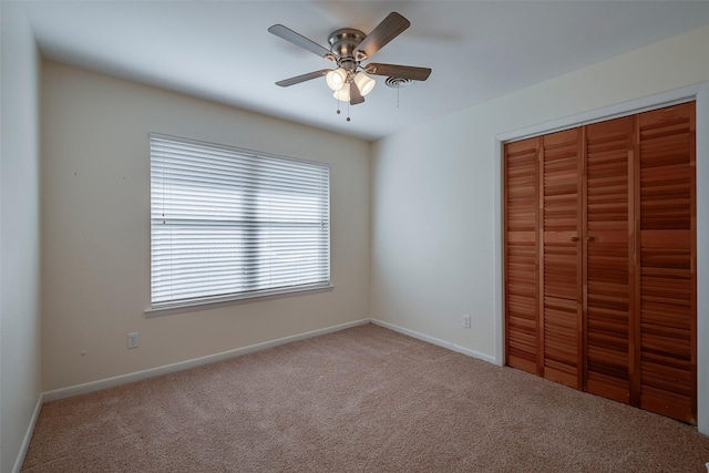 unfurnished bedroom featuring ceiling fan, a closet, and carpet