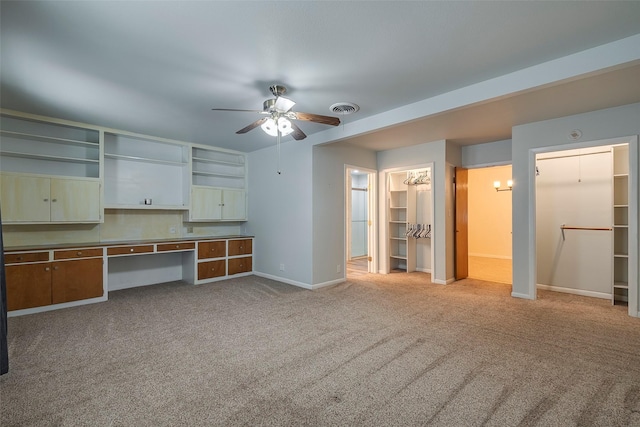 kitchen featuring ceiling fan, light colored carpet, and built in desk