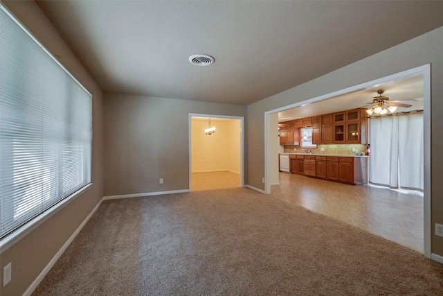 unfurnished living room with ceiling fan with notable chandelier, sink, and light carpet