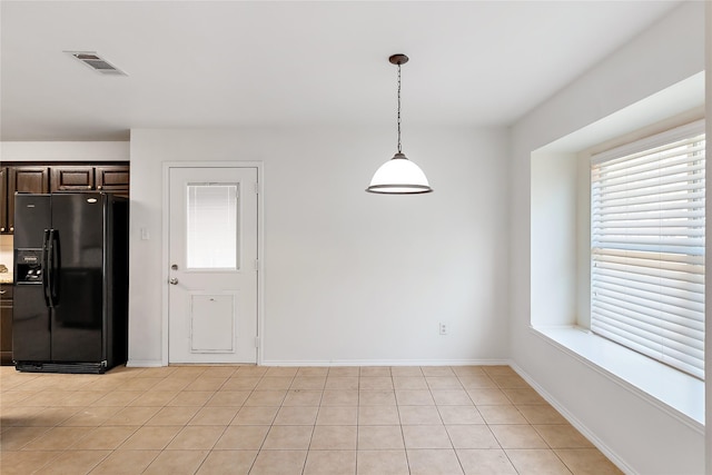 kitchen featuring black fridge, dark brown cabinets, decorative light fixtures, and light tile patterned flooring