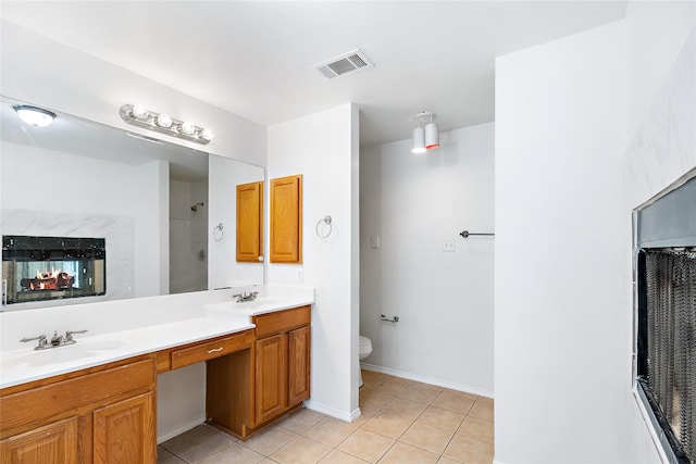 bathroom featuring toilet, vanity, tile patterned floors, and walk in shower