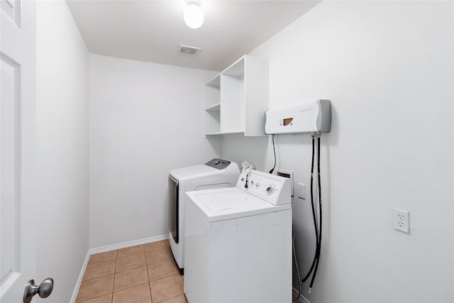 laundry room featuring washing machine and dryer and light tile patterned flooring