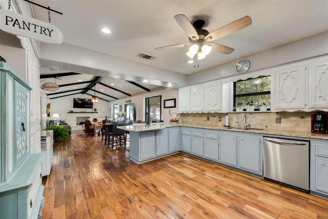 kitchen with sink, vaulted ceiling with beams, ceiling fan, kitchen peninsula, and stainless steel dishwasher