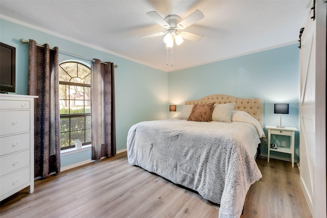 bedroom featuring crown molding, ceiling fan, light hardwood / wood-style floors, and a textured ceiling