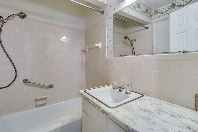 bathroom featuring tiled shower / bath, backsplash, and vanity