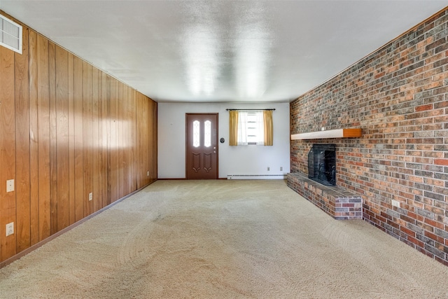 unfurnished living room featuring wooden walls, a fireplace, brick wall, baseboard heating, and light colored carpet