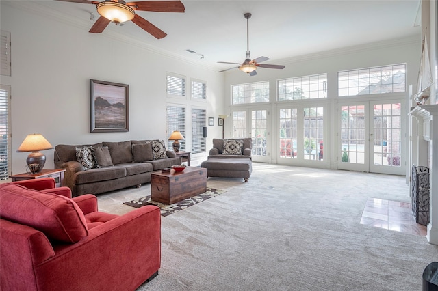 carpeted living room with crown molding, ceiling fan, french doors, and a high ceiling