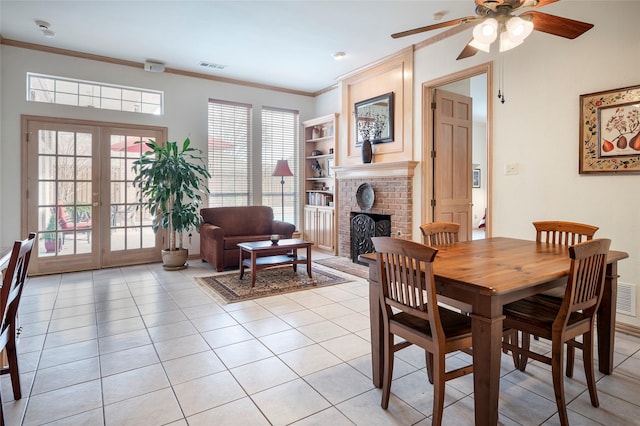 dining space featuring crown molding, light tile patterned floors, a fireplace, and french doors