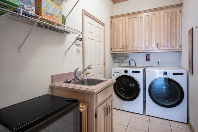 clothes washing area with cabinets, sink, washing machine and dryer, and light tile patterned floors