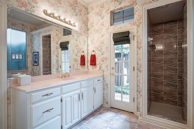 bathroom featuring ornamental molding, a healthy amount of sunlight, vanity, and a tile shower