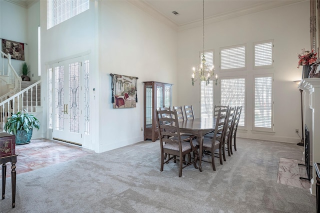 carpeted dining space featuring crown molding, a chandelier, and a high ceiling