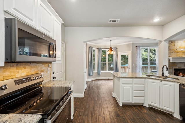 kitchen featuring a notable chandelier, sink, white cabinetry, light stone countertops, and appliances with stainless steel finishes