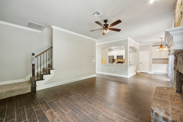 unfurnished living room with ceiling fan with notable chandelier and crown molding