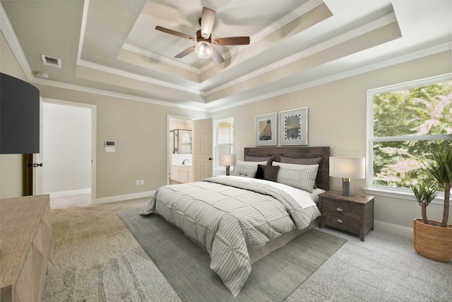 carpeted bedroom with ceiling fan, multiple windows, connected bathroom, and a tray ceiling