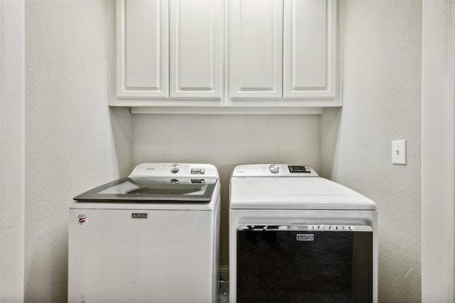 clothes washing area featuring independent washer and dryer and cabinets