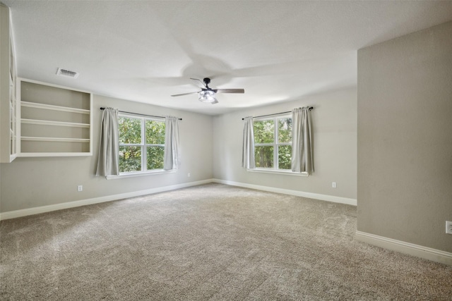 unfurnished room featuring ceiling fan, a wealth of natural light, and carpet