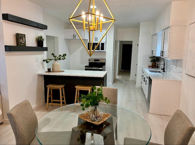 dining area with sink, an inviting chandelier, and light hardwood / wood-style flooring