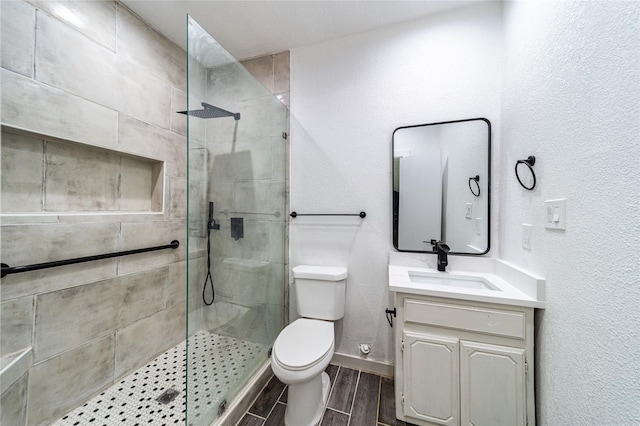 bathroom featuring toilet, a tile shower, and vanity