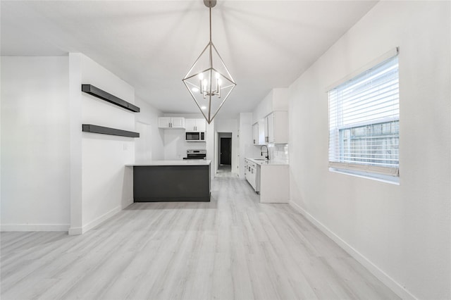 kitchen featuring stainless steel electric range, a notable chandelier, white cabinets, light hardwood / wood-style flooring, and decorative light fixtures