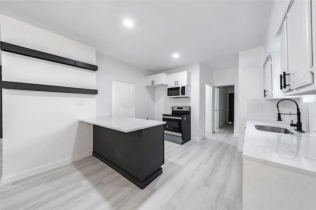 kitchen with light stone counters, white cabinets, stainless steel electric stove, and sink