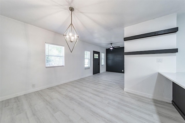 interior space featuring ceiling fan with notable chandelier and light wood-type flooring