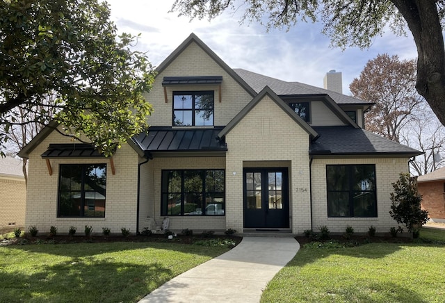 view of front of property featuring a standing seam roof, a chimney, metal roof, and a front yard