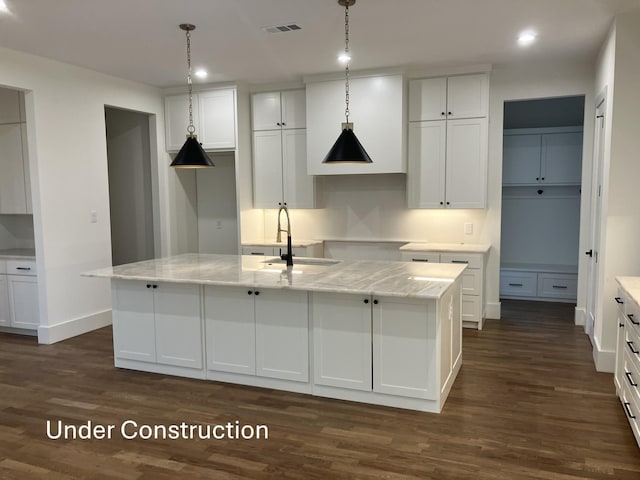 kitchen featuring visible vents, white cabinets, an island with sink, dark wood-style flooring, and a sink