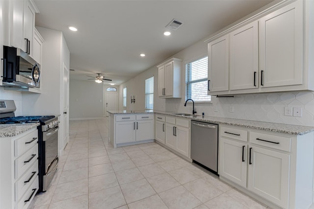 kitchen with sink, white cabinets, ceiling fan, kitchen peninsula, and appliances with stainless steel finishes