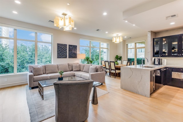 living room featuring sink, a notable chandelier, and light hardwood / wood-style flooring