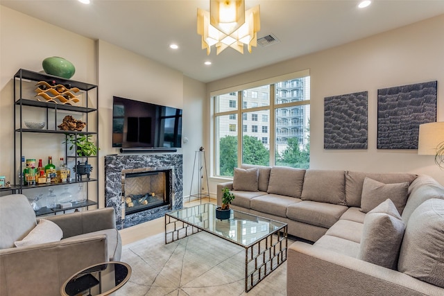 living room featuring a high end fireplace, a chandelier, and light wood-type flooring