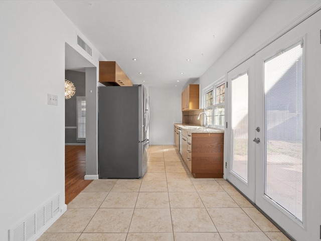 kitchen featuring stainless steel appliances, french doors, light tile patterned flooring, and light stone countertops