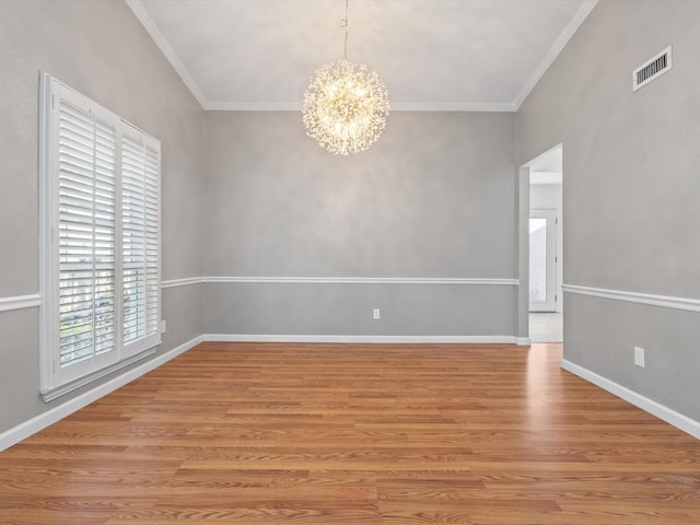 spare room with an inviting chandelier, light wood-type flooring, and ornamental molding