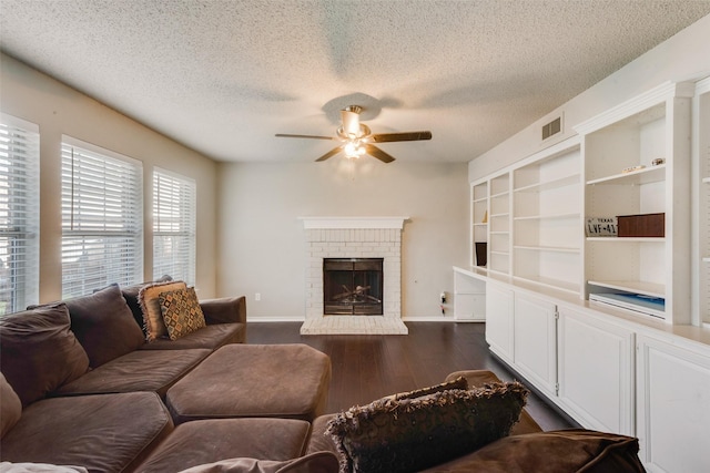 living room with a textured ceiling, a brick fireplace, dark hardwood / wood-style flooring, built in features, and ceiling fan