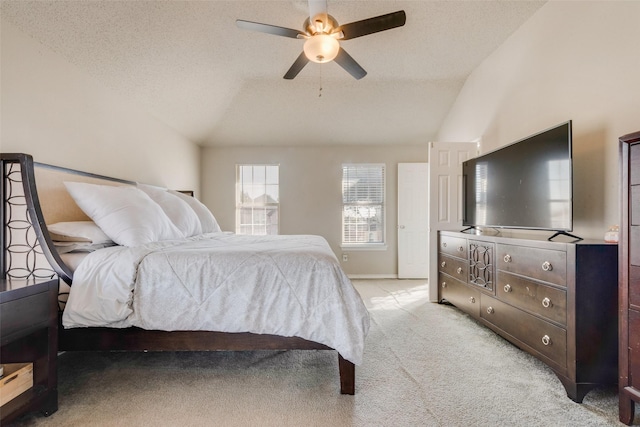 bedroom with lofted ceiling, a textured ceiling, ceiling fan, and light carpet