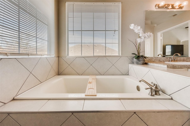 bathroom featuring tiled bath and vanity