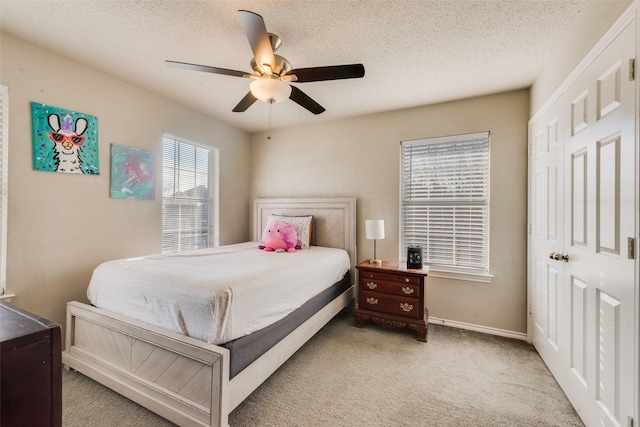 bedroom with a closet, light carpet, ceiling fan, and a textured ceiling