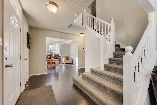 foyer featuring a textured ceiling, a chandelier, and dark hardwood / wood-style floors