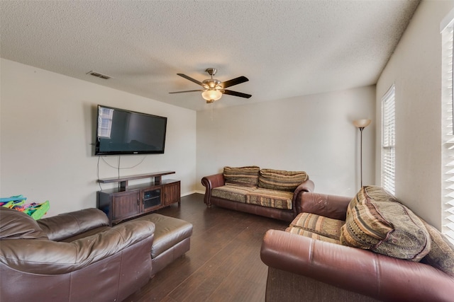 living room with a textured ceiling, ceiling fan, and dark hardwood / wood-style floors