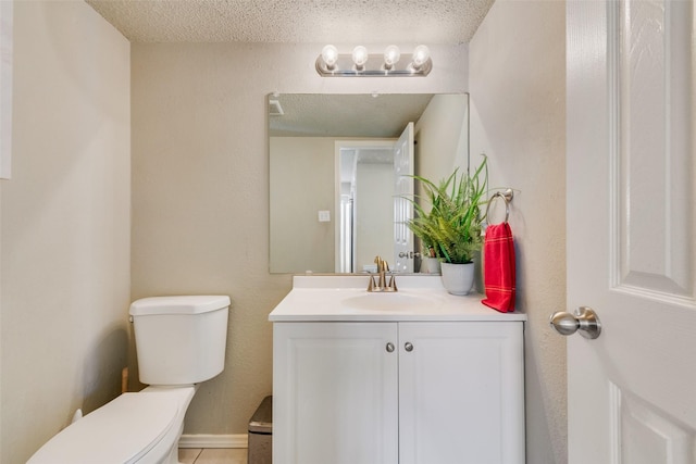 bathroom with a textured ceiling, vanity, and toilet