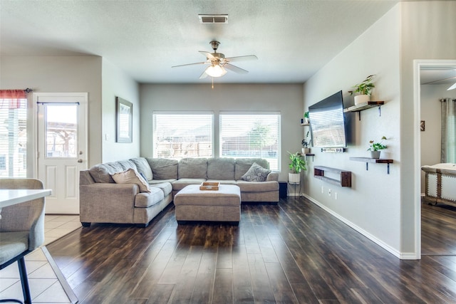 living room with a textured ceiling, ceiling fan, and dark hardwood / wood-style floors