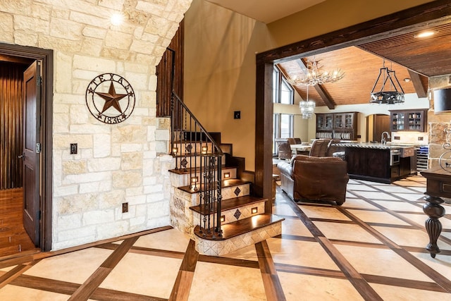 interior space featuring an inviting chandelier, beam ceiling, wooden ceiling, and sink