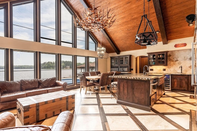 living room with high vaulted ceiling, an inviting chandelier, beam ceiling, and a water view